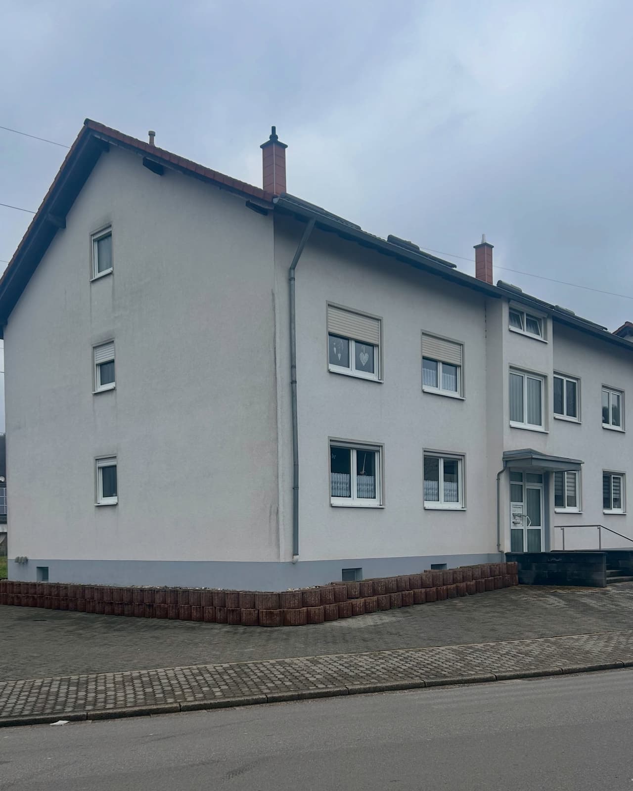 Mehrfamilienhaus mit verwitterter Fassade vor dem Anstrich