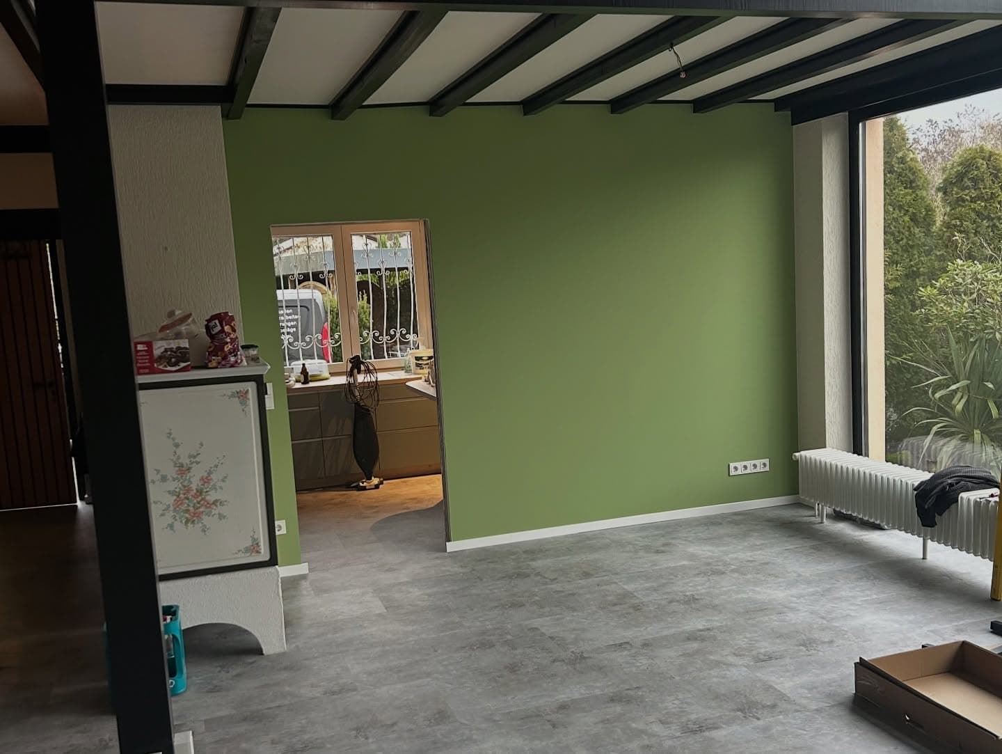 Neu gesetzte Wand mit grünem Anstrich zwischen Küche und Wohnzimmer